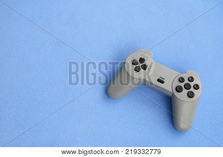 Playing games concept. Single pad joystick lies on the blanket of furry blue fleece fabric. Controller for video games on a background texture of light blue soft plush fleece material