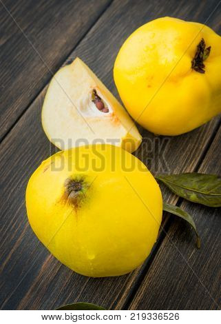 Ripe quince or queen apple autumn fruits with leaves on dark rustic wooden background