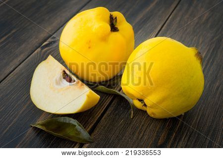 Yellow quince or queen apple autumn fruits with leaves on dark rustic wooden background closeup