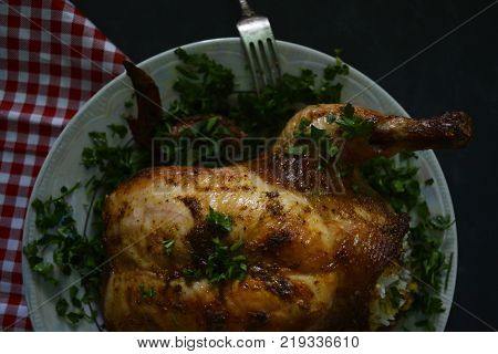 roast in the oven chicken with garnish on a platter with greens
