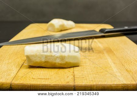 Peeled parsley root prepared for cutting on a chopping board.