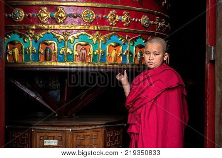 THAMEL, KATHMANDU, NEPAL - OCTOBER 18, 2015 : Novice monk rotating a large praying wheel in a temple in Kathmandu