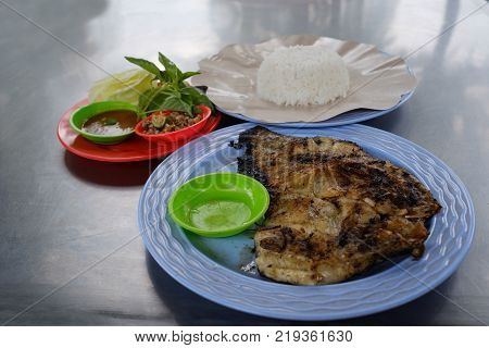 Grilled fish in blue plasti plate with white rice. Traditional food of Bali in Indonesia