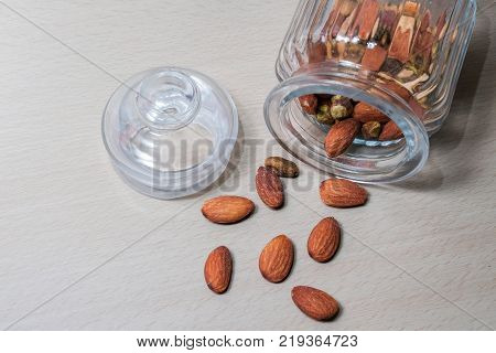 Delicious almonds fall from the glass bottle.