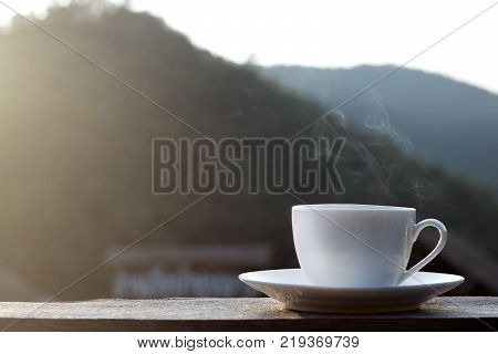 cup of hot coffee for brackfast on wooden balcony near river and mountain background