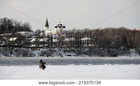 Winter view on the Volga River in Yaroslavl, Russia, fisherman on the ice of the freezing Volga at the beginning of winter and Trinity Church on the shore, in the background