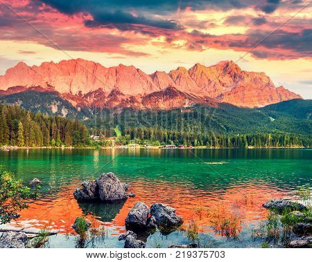 Colorful summer sunset on the Eibsee lake with Zugspitze mountain range. Splendid outdoor scene in German Alps Bavaria Garmisch-Partenkirchen village location Germany Europe. Artistic style post processed photo.