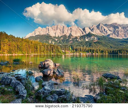 Sunny summer morning on the Eibsee lake with Zugspitze mountain range. Splendid outdoor scene in German Alps Bavaria Garmisch-Partenkirchen village location Germany Europe. Artistic style post processed photo.