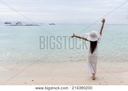 Asian girl in wearing white dress Standing on the sea beach solitude alone on the beach. Sea in summer. Single woman walking at beach relaxing vacation