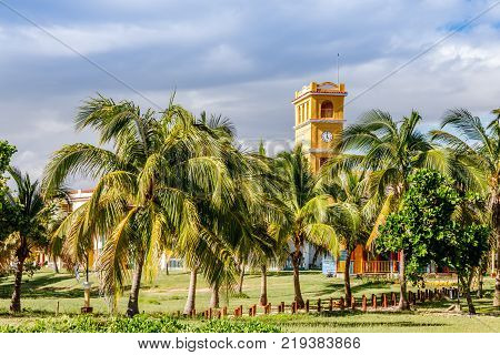 Yellow clock tower with palms at the front close to Ancon beach Trinidad Cuba
