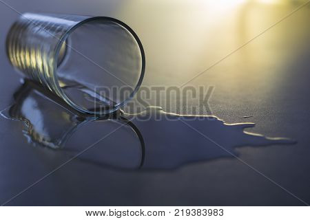 an empty glass with spilled water lies on a gray table close-up