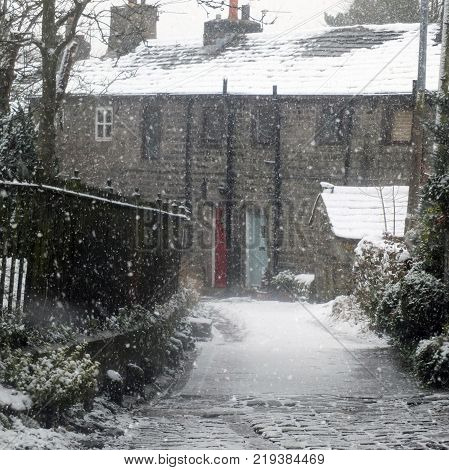 the village of heptonstall in snowfall showing ancient houses and small lane