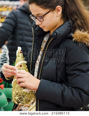 Cheerful girl in glasses with diopters choosing gifts at Christmas fair