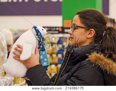 Cheerful smiling girl in glasses with diopters choosing gifts at Christmas fair