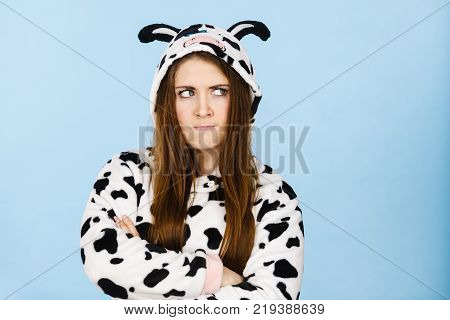 Teen girl in funny nightclothes pajamas cartoon style showing angry offended face expression studio shot on blue. Negative emotion concept.