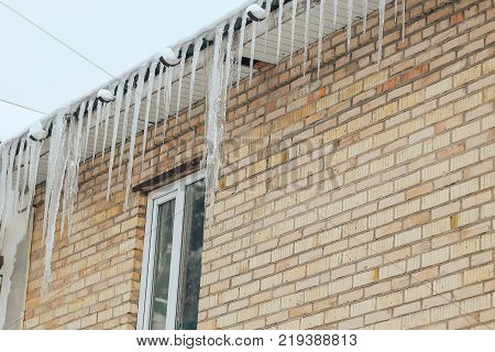 Many dangerous icicles hang on the roof of the building. Dangerous icicles