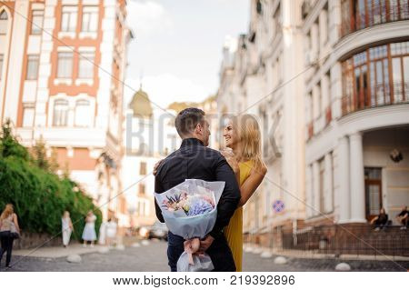 pretty blonde girl with a bouquet of flowers including roses astilba carnations and hydrange hugs her boyfriend