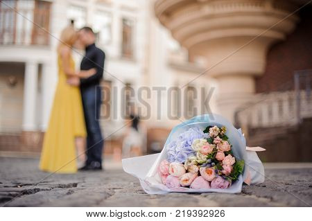 pretty blonde girl with a bouquet of flowers including roses astilba carnations and hydrange hugs her boyfriend