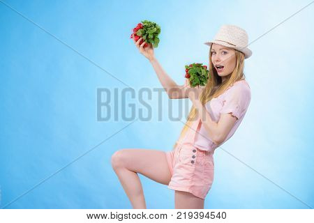 Happy cheerful teenage young woman ready for summer wearing pink outfit and sun hat holding delicious radish
