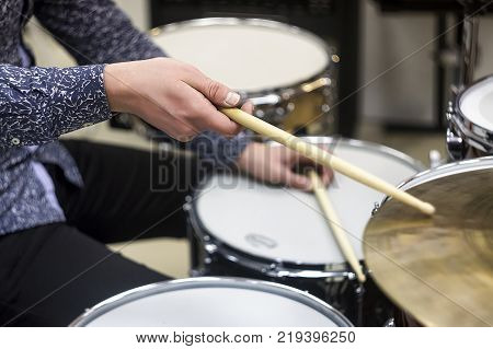 Detail of a drummer dressed in red costume with medieval clothes. Wooden chopsticks are held firmly in hand. The musical instrument is finished in wood therefore very heavy.