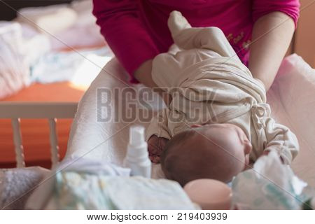 the mother replaces the babies' nappies on the baby on the table provided for it