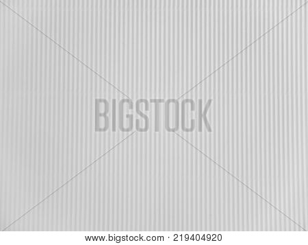 Off white vertical corrugated paper texture closeup.