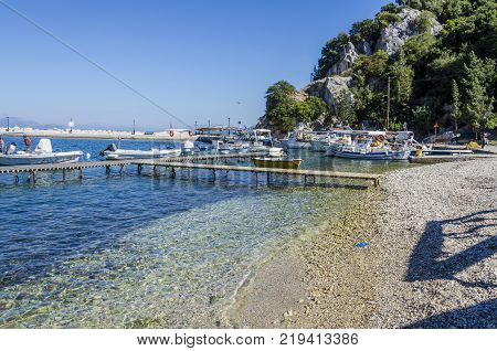 small wooden dock for boats and sports boats on the beach near the port of frikes ithaka and in the background the mountain that falls into the sea
