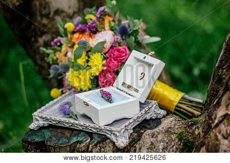 The wedding rings on nature with flowers.
