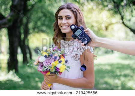 Photographer measuring light with light meter on beautiful girl.