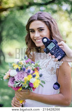 Photographer measuring light with light meter on beautiful girl.