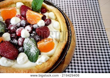 Danish pancake with berries and whipped cream topping covered with sugar powder