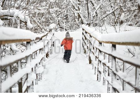 Little Cheerful Boy Runs In Winter On Bridge.
