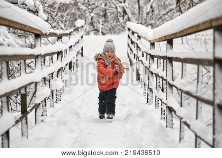 Little Cheerful Boy Runs In Winter On Bridge.