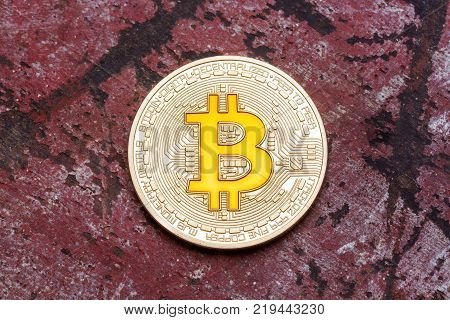 Golden cryptocurrency yellow bitcoin on red background, close up. High resolution photo.