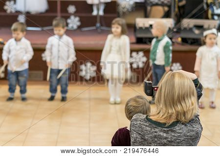 A woman takes pictures on DSLR performance of children in bright costumes