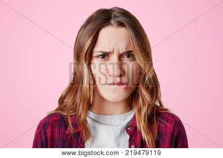 Headshot Of Unhappy Sorrorful Female Curves Lips, Looks Desperately At Camera, Being Upset To Hear B