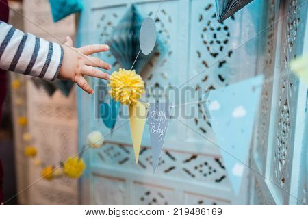 the child's hand stretches to the festive decor of cardboard in honor of the birthday.