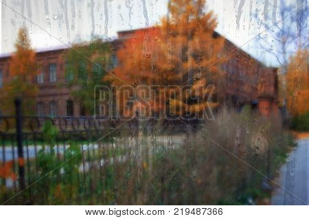 Autumn street on a rainy day view through wet glass