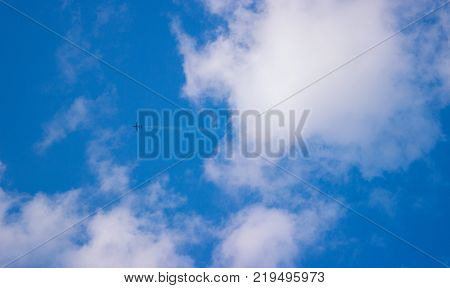 airplane in the blue sky between the white clouds
