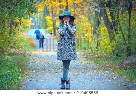 smiling girl in a hat stands on a trail in the forest