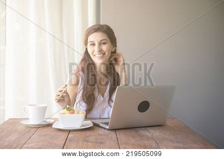 Woman having coffee and working outside. Working on laptop during her vacation in a tropical hotel. 