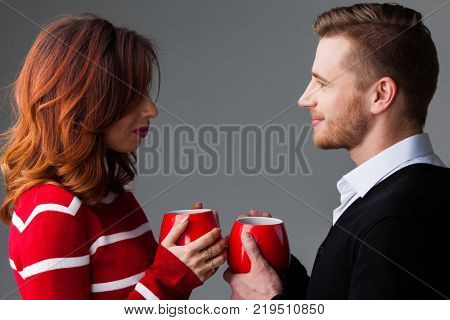 Young couple holding red coffee mags, Valentine's day concept