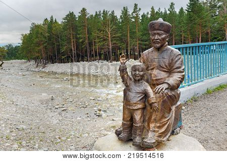 Arshan Russia - August 15 2017: Statue of Man with Child at the bridge over the Kyngyrga River. Buryatia