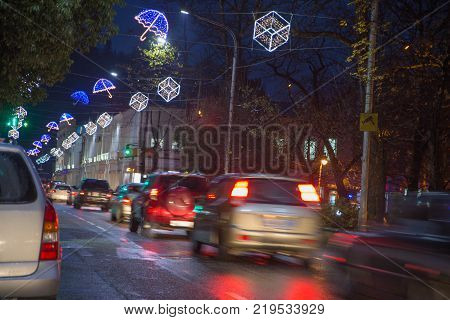 Night traffic cars on highway road on sunset evening night in busy city urban view. Christmas in Town. Night scene of city road in Kutaisi