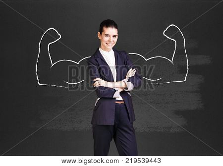 Business woman stands over chalkboard with drawn powerful hands.