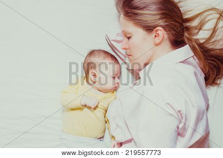 co-sleeping mother and three months baby after breastfeeding on the bed