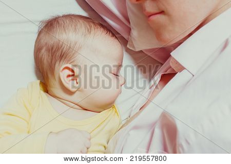 co-sleeping mother and three months baby after breastfeeding on the bed