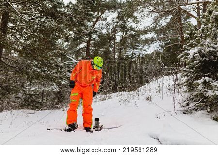 Snowboarder checks his equipment in the winter forest