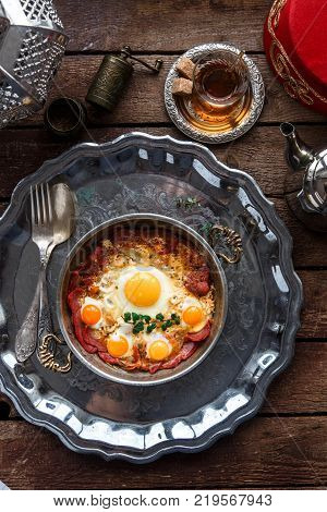 Turkish basturma with fried egg in a copper pan, rustic style.