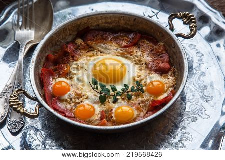 Traditional turkish breakfast with eggs and pastirma, with tea and metal dishware.